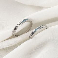 two wedding rings sitting on top of a white cloth