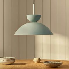 a wooden table topped with two bowls and a light hanging from the ceiling over it