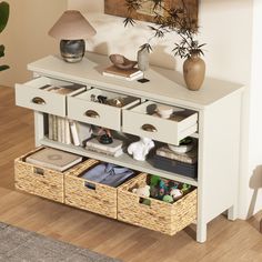 a white cabinet with drawers and wicker baskets on it in a living room area