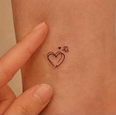 a small heart tattoo on the side of a woman's left arm and wrist