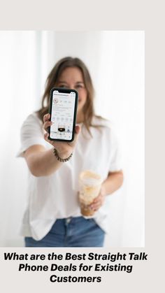 a woman in white shirt holding up a cell phone