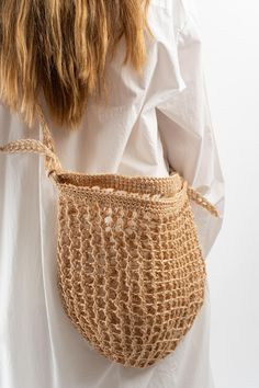 a woman is holding a crocheted bag in her hands and wearing a white shirt