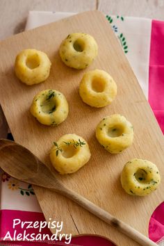 small doughnuts are arranged on a cutting board with a wooden spoon next to them