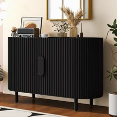 a black sideboard in a living room next to a potted plant and mirror