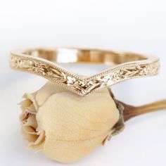 two gold wedding bands sitting on top of a flower