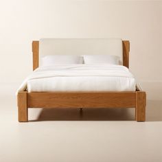 a wooden bed with white sheets and pillows