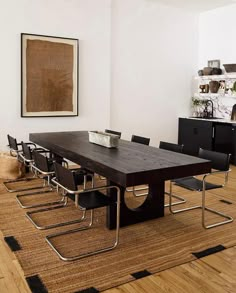 a dining room table with black chairs and a brown rug in front of the table