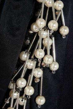 a bunch of pearls are attached to some metal pins on a black jacket with white buttons