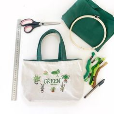 a green bag with scissors, thread and other crafting supplies laid out next to it