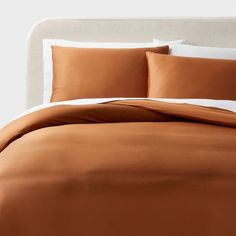 the bed is made with brown sheets and pillows