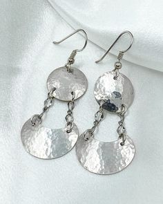 Simple and elegant, these shiny silver dangles were hand crafted from quality sterling silver sheet metal. These earrings feature silver discs at the top that are attached by chains to silver half moons below. The discs and half moons are slightly domed with a hammered texture to add sparkle. They are then polished to a mirror finish. The sterling silver ear wires feature a silver ball and coiled wire.  These silver dangle earrings are 2 1/4 inches long. They are lightweight and perfect for everyday or evening wear! They arrive gift boxed, ready for gifting yourself or a friend. Nickel Free Silver Round Disc Earrings, Nickel-free Silver Round Disc Earrings, Silver Nickel-free Round Disc Earrings, Hammered Sterling Silver Round Disc Earrings, Silver Metal Dangle Chandelier Earrings, Silver Hammered Drop Earrings, Handmade Silver Chandelier Earrings For Anniversary, Hammered White Gold Sterling Silver Earrings, White Gold Hammered Sterling Silver Earrings