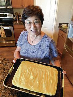 an older woman holding a pan with cake in it