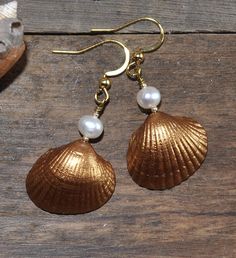 "Stylish earrings with beautiful gold painted seashells and white freshwater pearls. 18K gold plated nickel-, lead- and cadmium-free stainless steel hooks. Measure about 30mm (1,2\") from the lower part of the hook. These earrings will come in a pretty organza gift bag ready for gifting! If you have any questions just convo me and I will get back to you as soon as possible. Thanks for looking // Mari" Elegant Gold Shell With Pearl Charm, Adjustable Gold Shell, Ocean-inspired Gold Shell-shaped Jewelry, Gold Shell Dangle Earrings, Shell-shaped Pearl Earrings For Gift, Gold Shell-shaped Brass Earrings, Gold Brass Shell-shaped Earrings, Elegant Shell For Jewelry Making, Elegant Shell-shaped Brass Jewelry