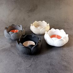 three bowls are sitting on the floor next to each other, one has an orange candle in it