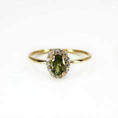 a yellow gold ring with an oval shaped green diamond surrounded by small white and brown diamonds