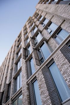 a tall brick building with lots of windows on it's side and a clock at the top