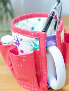 a close up of a cup on a table with a pen and scissors in it