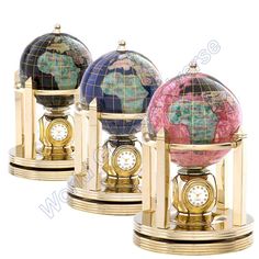 three clocks with different colored globes sitting on top of each other in front of a white background