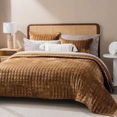 a bed with brown bedspread and pillows in a bedroom next to two nightstands