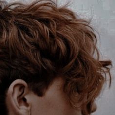 the back of a person's head with curly hair in front of them and behind it is a white wall