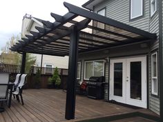 an outdoor patio with table, chairs and grill on the wooden decking area next to a house