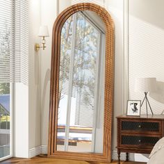 a large mirror sitting on top of a wooden floor next to a dresser and lamp