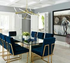 a dining room table with blue chairs and artwork on the wall