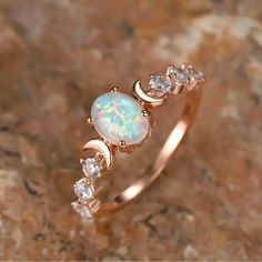 an opal and diamond ring sitting on top of a rock