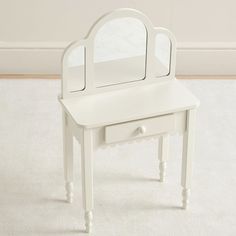 a white vanity table with a mirror on it