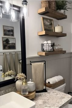 a bathroom with two shelves above the toilet and a sink in front of a mirror