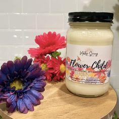 a jar of flower child sitting on top of a wooden table next to some flowers