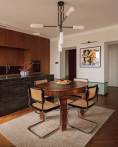 a dining room table with four chairs and a bowl of fruit on top of it