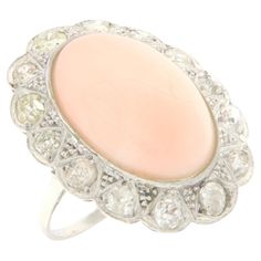 This exquisite ring in 18-karat white gold evokes the timeless elegance of antique style, offering a perfect balance between classicism and contemporary charm. At the heart of this majestic creation stands a spindle of pink coral, chosen for its delicate color and extraordinary natural beauty. The pink coral, symbolizing modesty and immortality, gives the ring a vibrant heart, rich in history and meaning. Surrounding this central gem, old-cut diamonds add another layer of splendor and mystery. T Classic Wedding Jewelry With Cabochon, Elegant Rings With 17 Jewels, Elegant White Gold Cluster Ring With Polished Finish, Classic Jewelry With Diamond Accents And Oval Cabochon, Antique Platinum Gemstone Rings, Antique Platinum Ring With Gemstone, Fine Jewelry Platinum Cabochon, Fine Jewelry In Platinum With Cabochon, Antique Oval 14k White Gold Jewelry