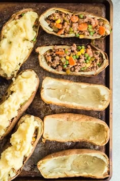 baked potatoes on a baking sheet with meat and vegetables in the middle, ready to be cooked