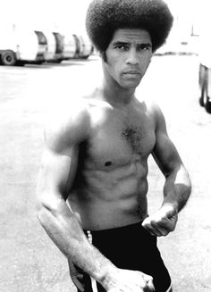 a black and white photo of a shirtless man holding a skateboard