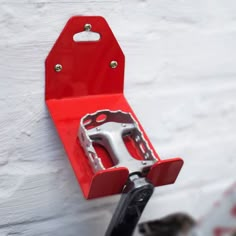 a pair of scissors hanging on the side of a white wall with a red handle