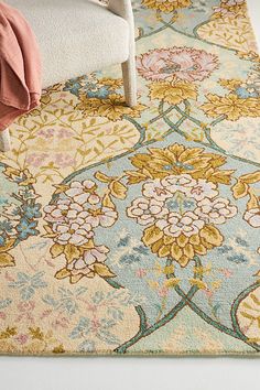 an area rug with flowers on it and a chair in the corner next to it