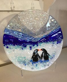 a glass plate with two penguins in the ocean on it's side and blue bubbles