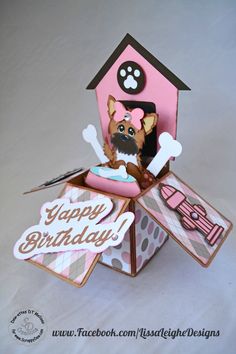 a dog is sitting in a box with a happy birthday card