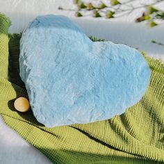 a blue heart shaped pillow sitting on top of a green blanket