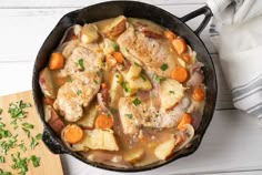 a skillet filled with chicken, potatoes and carrots