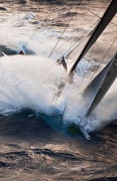 two sailboats in the water splashing up and over each other's sails