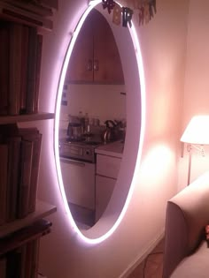 a living room with a couch and a round mirror on the wall next to a book shelf