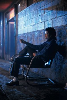 a man sitting on a chair in front of a brick wall