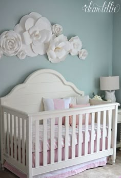 a white crib with flowers on the wall above it in a baby's room