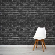 a white chair sitting on top of a wooden floor next to a black brick wall