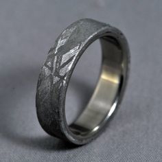 a wedding ring with an etched design on it's side, sitting on a gray surface