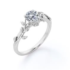 a white gold engagement ring with leaves on the band and a round diamond center stone