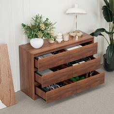 a wooden cabinet with drawers and plants in it next to a planter on the floor