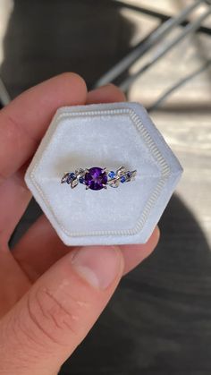 a person holding a ring in their hand with an amethorate and blue sapphire